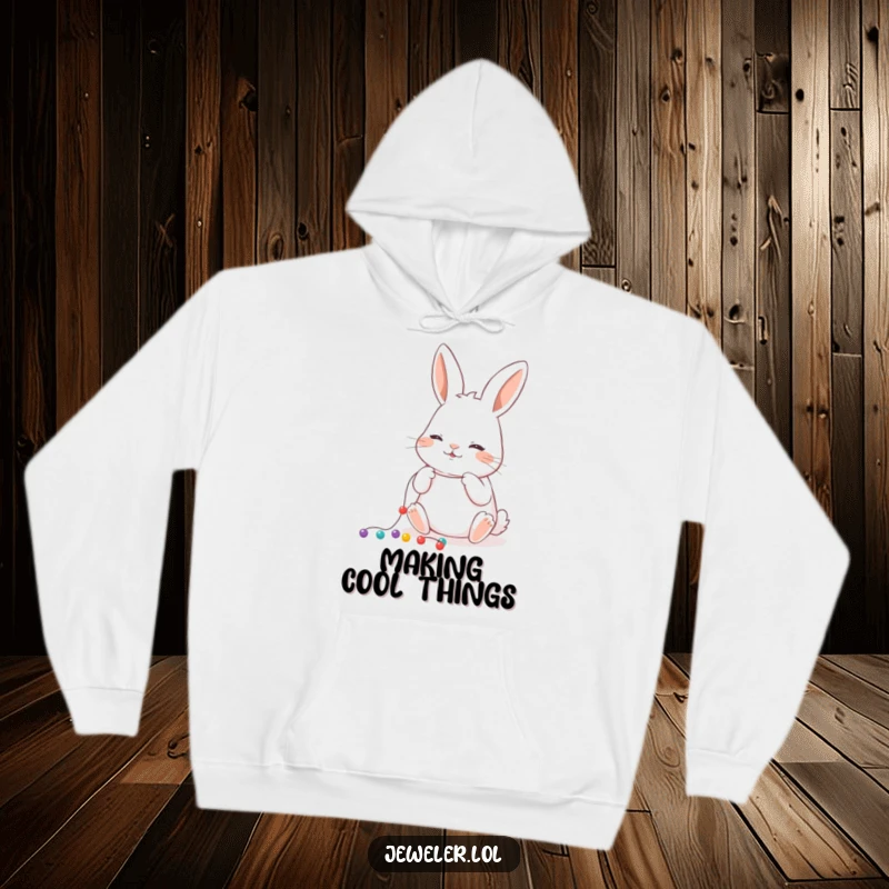 Funny Hoodie of a playful rabbit carefully threading tiny beads onto a string, ideal for crafters and art lovers.